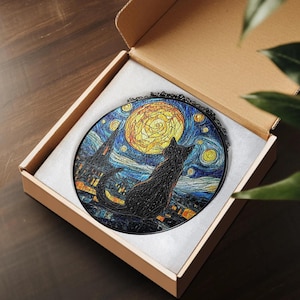 May include: A round, black cat silhouette gazing at a yellow moon and starry night sky, reminiscent of Van Gogh's "Starry Night." The artwork is set in a black frame and presented in a cardboard box with white padding. The cat is perched on a rooftop.