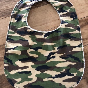 Puede incluir: Babero de bebé con estampado de camuflaje, forro de vellón blanco y cierre de presión.