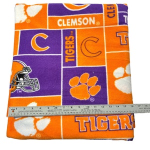 May include: Orange and purple fleece blanket with the Clemson Tigers logo and the words "Clemson Tigers" and "Clemson" repeated throughout.
