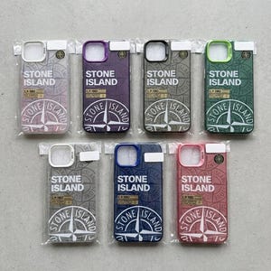 Peut inclure: Plusieurs coques de téléphone Stone Island de différentes couleurs, dont rose, bleu, vert et violet. Chaque coque présente le logo et la marque Stone Island, avec un motif de rose des vents. Les coques sont emballées dans du plastique transparent.