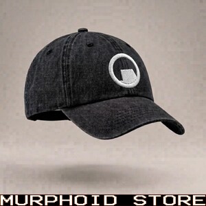 May include: A black baseball cap with a washed-out, distressed texture. The front panel features a white embroidered circular logo containing a stylized lambda symbol. The cap has a curved brim, a button on the crown, and stitched eyelets.