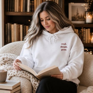 Peut inclure: Un sweat-shirt à capuche blanc à manches longues avec le texte read. dream. grow. imprimé en rouge foncé sur le haut de la poitrine gauche. Le vêtement comprend une capuche à cordon de serrage et une poche kangourou sur le devant.