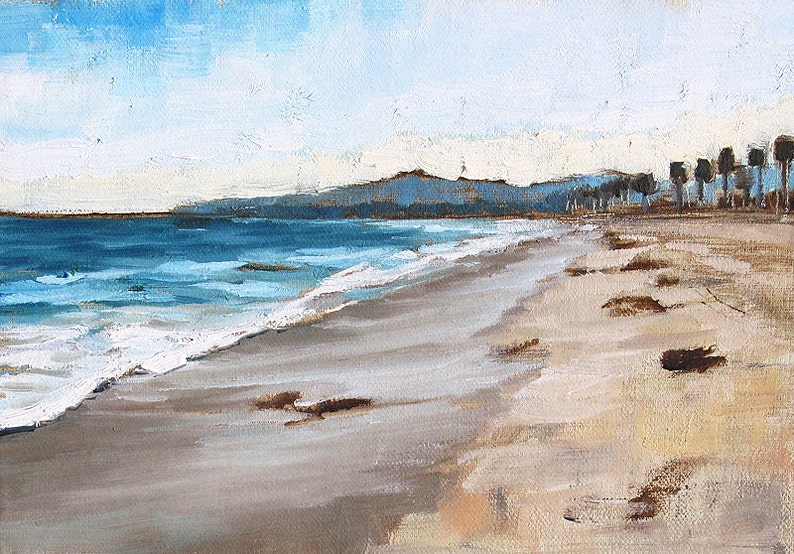 May include: Oil painting of a beach scene with a blue ocean and sky. The sandy beach has brown patches and the water has white waves. In the distance are mountains and trees. The artwork is painted with visible brushstrokes.