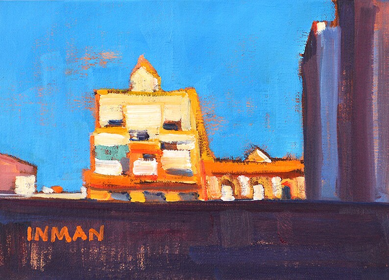 K&ouml;nnte beinhalten: &Ouml;lgem&auml;lde einer Stadtlandschaft mit leuchtend blauem Himmel. Die Geb&auml;ude sind in Orange-, Gelb- und Wei&szlig;t&ouml;nen gemalt. Der Name des K&uuml;nstlers, INMAN, ist unten in Orange zu sehen.