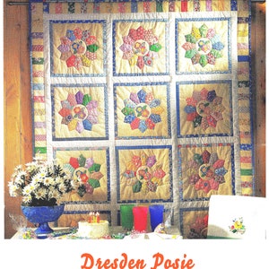 May include: A colourful quilt with a Dresden Posie pattern. The quilt is made up of nine squares, each with a different floral design. The quilt is hanging on a wooden wall.