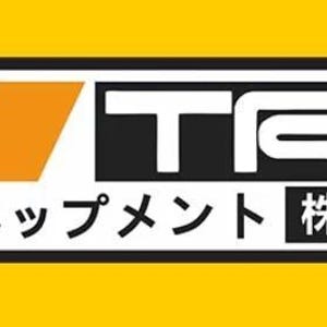 Op de afbeelding: Een rechthoekig logo met een rood parallellogram en een oranje parallellogram aan de linkerkant, gevolgd door de witte tekst TRD op een zwarte achtergrond. Daaronder staat de Japanse tekst トヨデベップメント 株式会社 op een witte achtergrond.