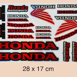 May include: A sticker sheet featuring various Honda logos, text, and wing emblems in red, black, and white. The designs include the Honda wordmark in different sizes and styles, along with motorsports branding. The sheet measures 28 x 17 cm.