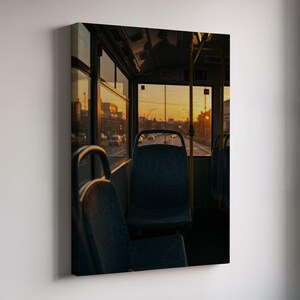 Könnte beinhalten: Innenansicht eines Busses mit blauen Sitzen und Blick auf die Straße. Die Fenster spiegeln die warmen Farben eines Sonnenuntergangs wider. Das Bild zeigt die Details des Businneren, einschließlich Haltestangen und Sitzen.