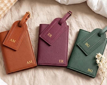 May include: Three rectangular passport holders in tan, plum, and dark green, each featuring a matching luggage tag. The items are embossed with gold initials AM, ER, and BG respectively on both the holder and the tag, showcasing a textured finish.
