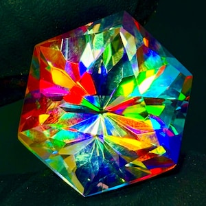 May include: A faceted gemstone with a complex, geometric design. The gem displays a vibrant spectrum of colors, including red, yellow, green, and blue, creating a dazzling display of light refraction. The shape is a multi-sided polygon.