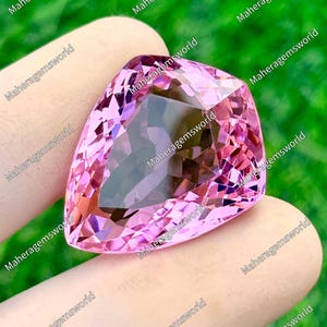 以下が含まれることがあります： 洋梨の形をしたファセットカットのピンク色の宝石で、光を反射する三角形や台形の面が多数施されています。鮮やかで半透明なピンクの色合いが特徴で、透明感のある磨き上げられた表面と、鋭く対称的なエッジが際立っています。