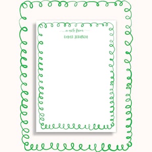 May include: A white notepad with a green, swirly border and the text "a note from Emma Johnson" in green script. The notepad is set within a larger green, swirly frame on a cream background. Stationery.