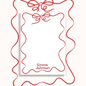 May include: White stationery with a red ribbon design. The stationery features a red ribbon border and two red bows at the top. The name "Emma Johnson" is printed in red at the bottom.