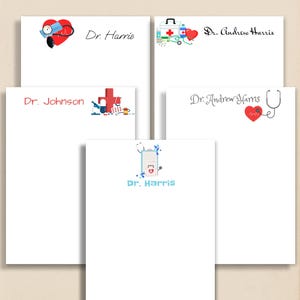 May include: White notepads with medical-themed designs. Each notepad features a different design, including a heart with a stethoscope, a medical kit, a cross, and a heart with a heartbeat line. The names "Dr. Harris" and "Dr. Johnson" are printed on the notepads.