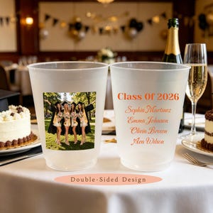 May include: Two frosted plastic cups featuring a double-sided design. One side displays a color photograph of four graduates in caps and gowns. The other side features the orange text Class Of 2026 followed by the names Sophia Martinez, Emma Johnson, Olivia Brown, and Ava Wilson.