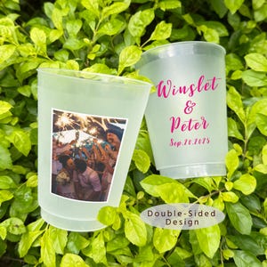 May include: Two frosted plastic cups featuring a double-sided design. One side displays a color photograph of a couple at a wedding with sparklers. The other side features the pink text Winslet & Peter and the date Sep. 20. 2025.