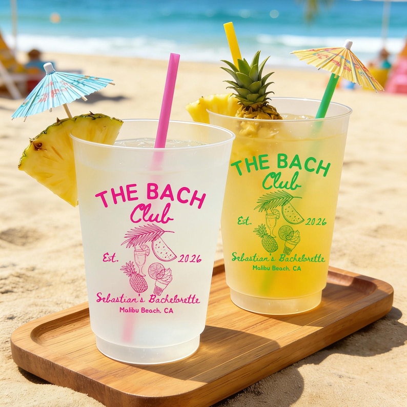 May include: Two clear plastic cups with pink and yellow straws, filled with drinks and garnished with pineapple slices and cocktail umbrellas. The cups have "THE BACH Club" printed on them, along with "Sebastian's Bachelorette Malibu Beach, CA."