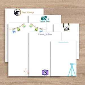 May include: A collection of white stationery featuring photography-themed designs. The designs include cameras, tripods, and photo prints. Some stationery pieces have the names "Emma Johnson" and "Andrew Harris" printed on them.