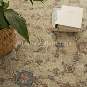 May include: A light green area rug featuring a repeating floral pattern in shades of blue, rust, and cream. The rug has a textured pile and is decorated with intricate botanical motifs throughout its surface, creating a detailed visual design.