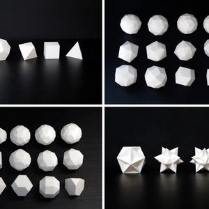 May include: A selection of white geometric forms, including spheres, polyhedrons, and pyramids, are displayed on a black surface. The shapes vary in size and complexity, showcasing a range of three-dimensional forms. The lighting highlights the facets and angles of each shape.