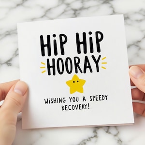 Peut inclure: Une carte de vœux blanche avec les mots "HIP HIP HOORAY" en noir, avec des accents jaunes et une étoile jaune. Le texte "WISHING YOU A SPEEDY RECOVERY!" est également sur la carte.