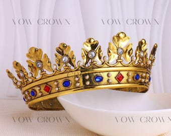 Op de afbeelding: Twee sierlijke gouden kronen met juwelen accenten, waaronder blauwe en rode stenen, worden getoond. De kronen staan tegen een witte achtergrond en in de buurt van een witte kom. De tekst "VOW CROWN" is zichtbaar. Copyright 2019 by VowCrown.