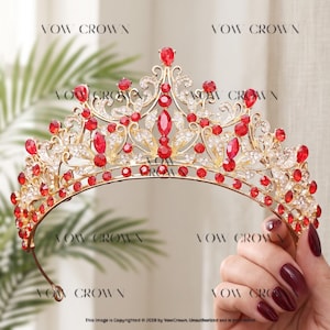 May include: A gold-toned tiara featuring intricate metal scrollwork, clear rhinestones, and numerous red teardrop and round crystals. The piece is marked with the text VOW CROWN repeated across the image. The design includes a central peak.