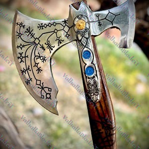 May include: A detailed axe with a silver blade and a wooden handle. The blade features intricate black etchings and a decorative design with blue and gold accents. The handle is dark brown with carved details.