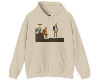 May include: Cream-colored hoodie with a front pocket and a drawstring hood. The graphic on the front depicts two figures in hats, one seated and one standing, with a drum set in the background. The figures are wearing plaid and striped shirts.