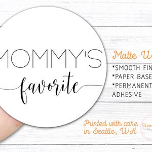 Round label is shown stuck on a fingertip.  Overlay text: ‘Matte White: Smooth finish, paper based, permanent adhesive. Printed with care in Seattle WA by Clementine Wedding & Party.'