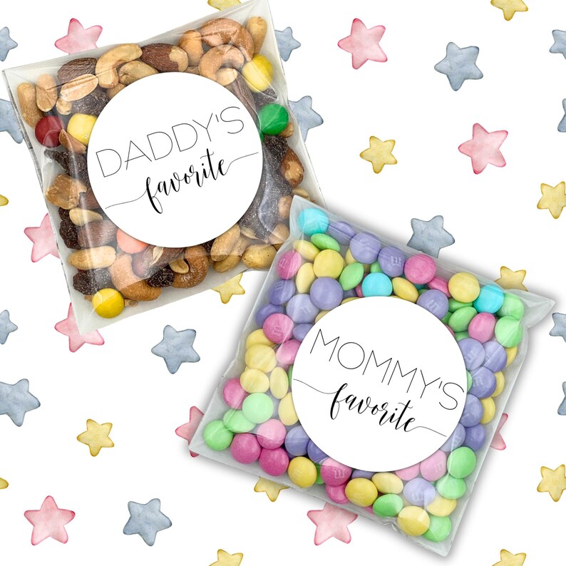 May include: Two clear plastic bags filled with snacks. One bag contains a mix of nuts and sweets with a white circle sticker that says "Daddy's favourite". The other bag contains colourful candy coated chocolate pieces with a white circle sticker that says "Mommy's favourite". Both bags are on a white background with a pattern of watercolour stars.