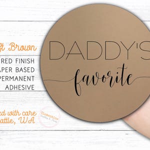 Round label is shown stuck on a fingertip.  Overlay text: 'Kraft Brown: Textured finish, paper based, permanent adhesive. Printed with care in Seattle WA by Clementine Wedding & Party.'