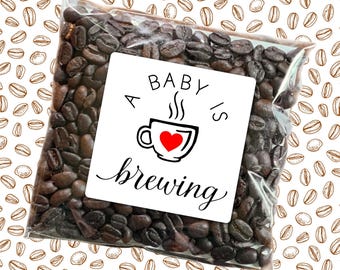 May include: A small clear bag filled with coffee beans with a white square label that says "A Baby is Brewing" with a red heart in a coffee cup graphic.