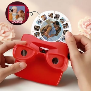 Op de afbeelding: Een rode retro-viewer met een cirkelvormige fotorol. De rol toont meerdere afbeeldingen, waaronder een centrale foto van een kussend stel met de tekst "I love You". De viewer heeft het woord "UPGRADE" naast een foto.