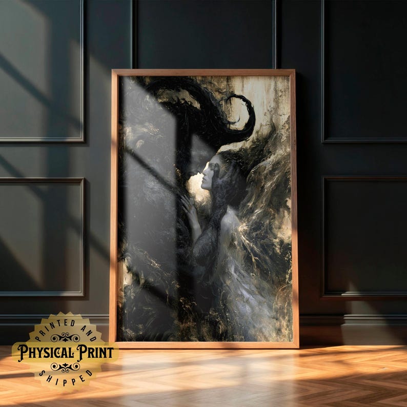 May include: A framed art print featuring a black and gold abstract image of a woman. The artwork has a dark, moody aesthetic with swirling patterns and a figure of a woman. The print is in a wooden frame and is displayed on a wooden floor.