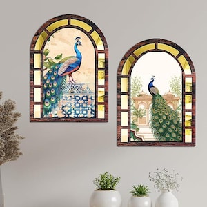 Könnte beinhalten: Zwei dekorative Wandkunstwerke mit Pfauenillustrationen. Jedes Stück ist in einer dunkelbraunen Bogenform mit goldenen Akzenten gerahmt. Die Pfauen sind mit leuchtend blauem, grünem und goldenem Gefieder dargestellt, vor einem Hintergrund mit einem verzierten architektonischen Design.