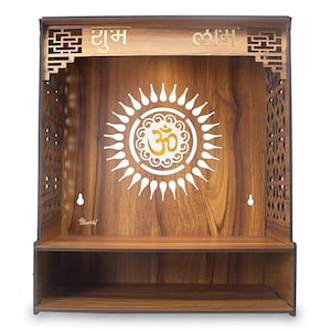 Op de afbeelding: Houten gebedsaltaar met een zonnesterontwerp en het Om-symbool in het midden. Het altaar heeft een plank en decoratieve uitsparingen aan de zijkanten en bovenkant. De woorden "Shubh" en "Labh" zijn boven de centrale opening gegraveerd.