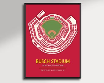 May include: A framed print featuring a detailed, top-down view of Busch Stadium in St. Louis, Missouri. The stadium's layout is rendered in white against a red background, with the text "BUSCH STADIUM" and coordinates. The print is enclosed in a black frame.