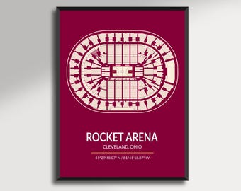 May include: A framed print featuring a detailed architectural layout of Rocket Arena in Cleveland, Ohio, against a deep red background. The arena's design is rendered in white, with the text "ROCKET ARENA" and location details below.