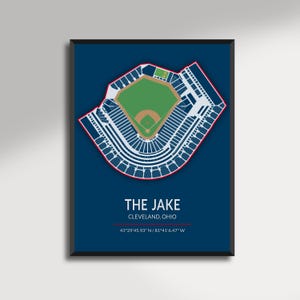 May include: A framed print featuring a detailed overhead view of a baseball stadium, rendered in white and red against a navy blue background. The text "THE JAKE, CLEVELAND, OHIO" is displayed below the stadium illustration, along with the coordinates.