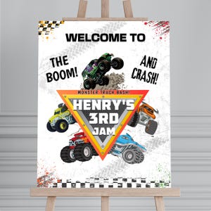Puede incluir: Un cartel rectangular blanco con cuatro camiones monstruo coloridos y un triángulo amarillo central. El texto dice: WELCOME TO THE BOOM! AND CRASH! MONSTER TRUCK BASH! HENRY'S 3RD JAM. El fondo incluye patrones de cuadros blancos y negros.