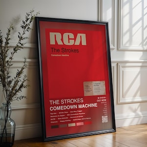 Può includere: Un poster incorniciato con sfondo rosso presenta il testo "RCA" e "The Strokes Comedown Machine" in bianco. Il poster include una tracklist e un piccolo adesivo con informazioni aggiuntive. La cornice è nera.