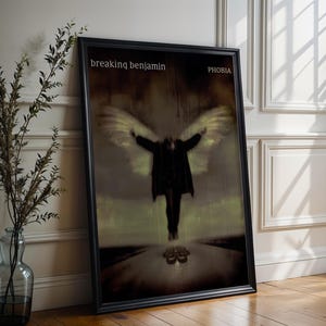 May include: Framed art print featuring the album cover for "Phobia" by Breaking Benjamin. The artwork depicts a figure with outstretched arms and angel wings, set against a muted, atmospheric background. The band's name and album title are displayed at the top.