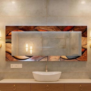 May include: A modern bathroom vanity with a large rectangular mirror. The mirror is framed with a mosaic of wood tones and orange accents. Two sconces with cream-colored shades flank the mirror. A white oval sink sits atop a wooden cabinet.