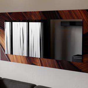 Op de afbeelding: Een rechthoekige wandspiegel met een decoratief houten frame. Het frame heeft een patroon van bruine en bruingele houtnerf. De spiegel reflecteert een uitzicht op een raam met witte verticale jaloezieën en een donkere binnenruimte.