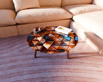 Op de afbeelding: Ovale salontafel met een geometrisch patroon van bruine, blauwe en bruine driehoeken. De tafel heeft houten poten. Een boek en een glas thee staan erop. De tafel staat voor een beige hoekbank.