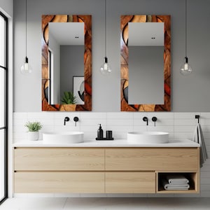 May include: Two rectangular mirrors with decorative wooden frames hang above a light wood vanity with two white sinks. The mirror frames feature a mosaic design with brown, orange, and black elements. The bathroom has a modern design.