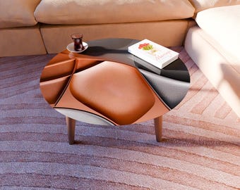 May include: A modern, round coffee table with a unique design. The table features a copper-colored, geometric patterned surface, a dark gray top, and wooden legs. A book and a glass of tea sit on top of the table.