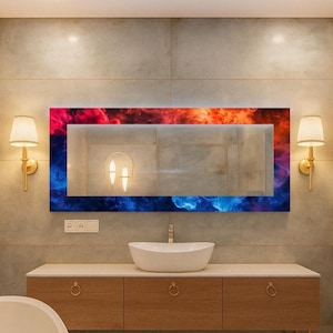 Op de afbeelding: Een moderne badkamer met een grote rechthoekige spiegel met een kleurrijk, abstract ontwerp in rood, oranje en blauw. De spiegel bevindt zich boven een houten wastafel met een witte wastafel. Twee wandkandelaars en een handdoekenrek zijn zichtbaar.
