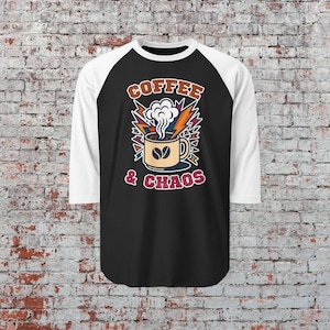 May include: Black and white raglan baseball tee with a graphic of a coffee cup with steam, lightning bolts, and the words "Coffee & Chaos" in a retro style. The shirt has white sleeves and a black body.